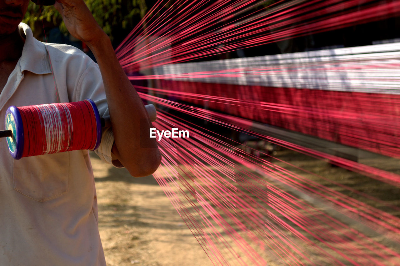 Man holding spool while standing by thread at field