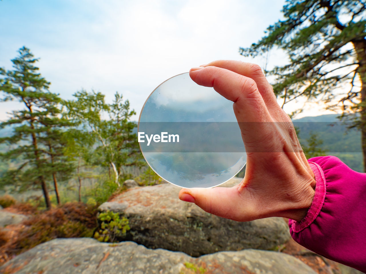Blurry mountains captured in glass ball reflection hold in fingers. saxon switzerland, deutschland