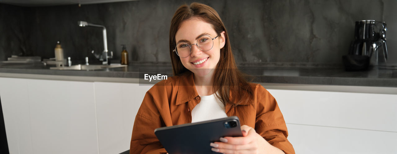 portrait of young woman using digital tablet while sitting at home