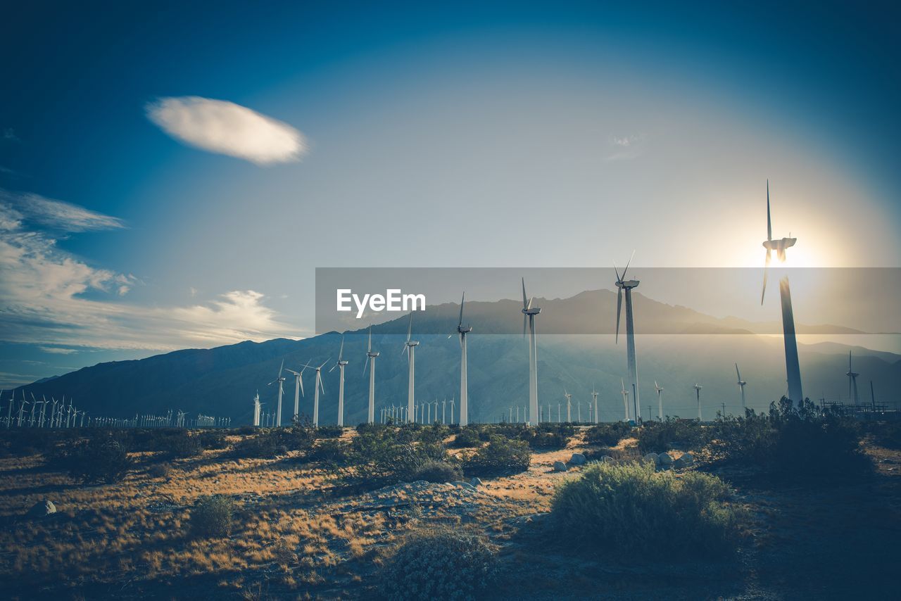 Scenic view of windmills on landscape against sky during sunset