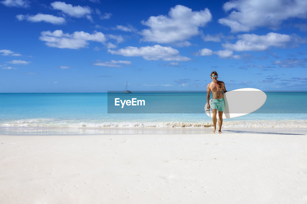 rear view of woman standing on beach against sky