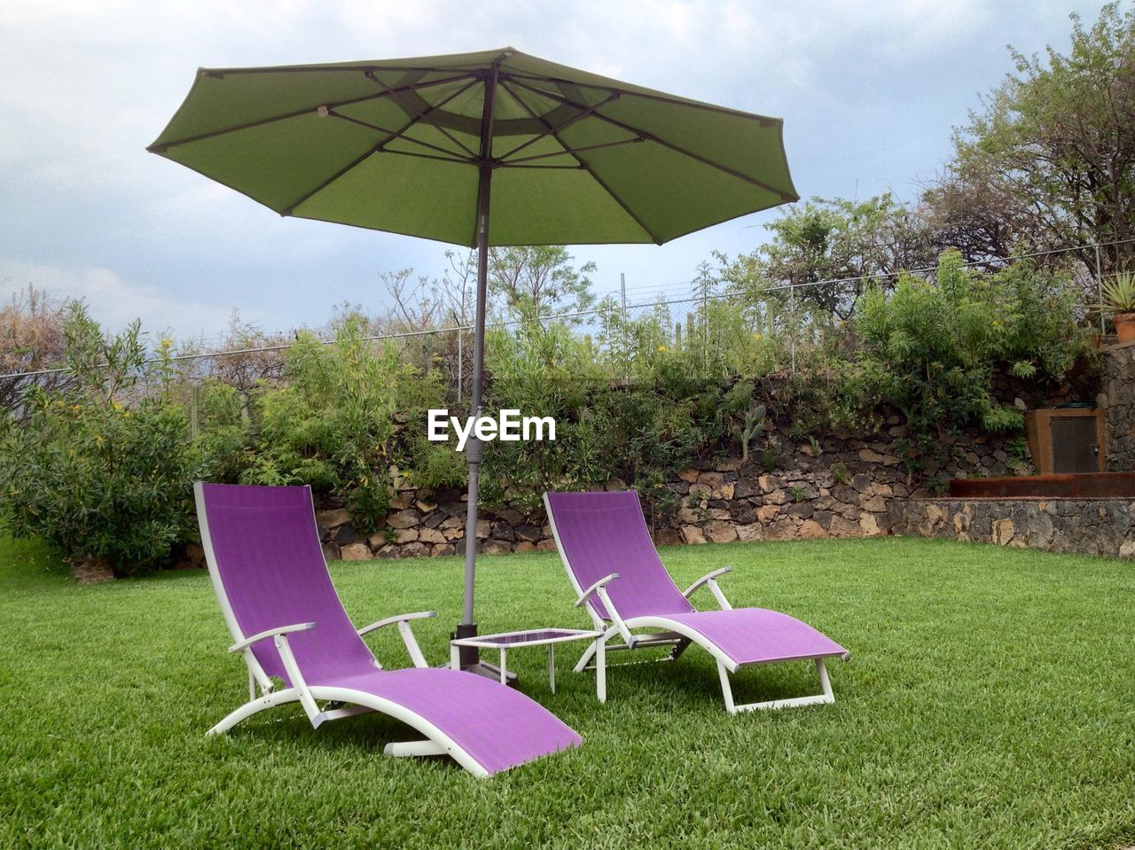 Patio umbrella with lounge chair in field