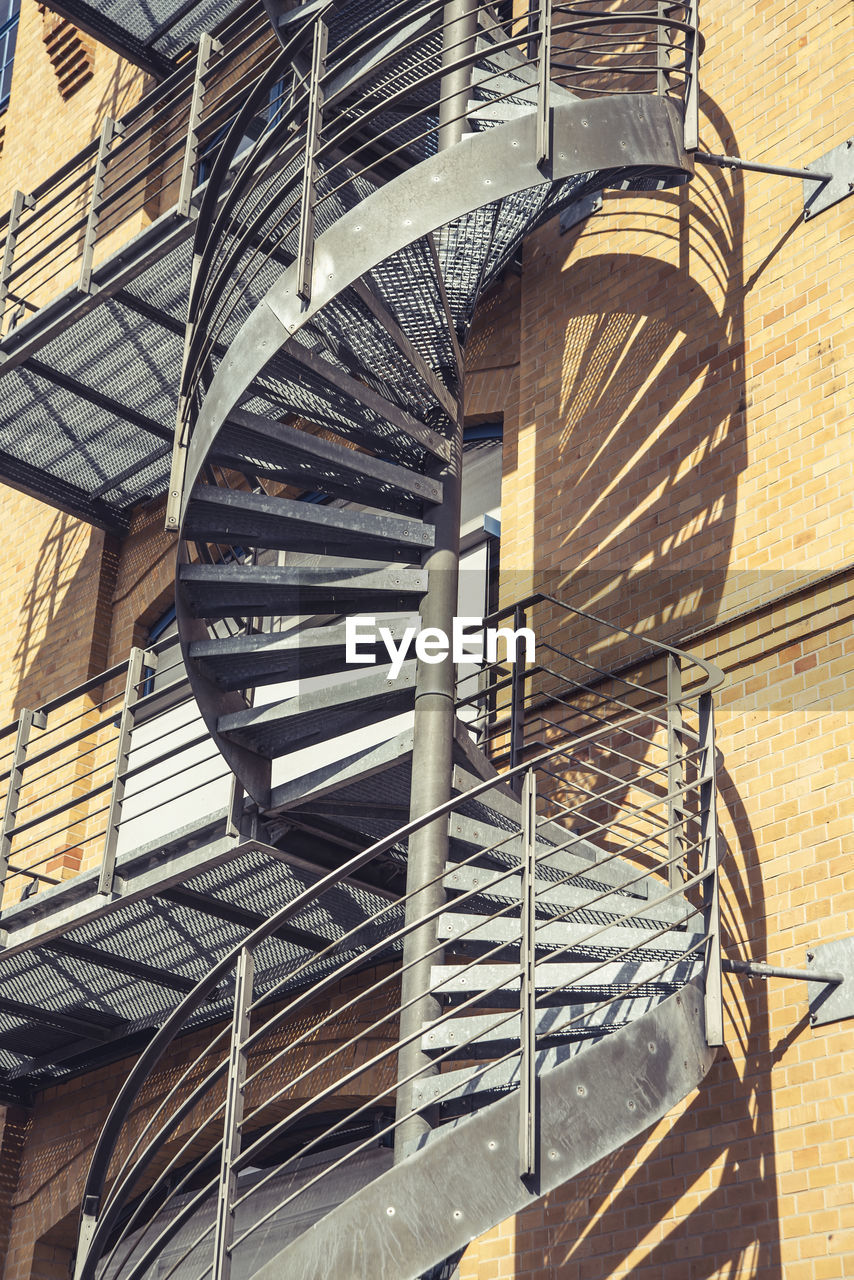 architecture, built structure, staircase, steps and staircases, building exterior, railing, fire escape, iron, no people, day, low angle view, spiral, sunlight, building, stairs, spiral staircase, facade, wood, outdoors, metal, shadow, wall, nature, wall - building feature