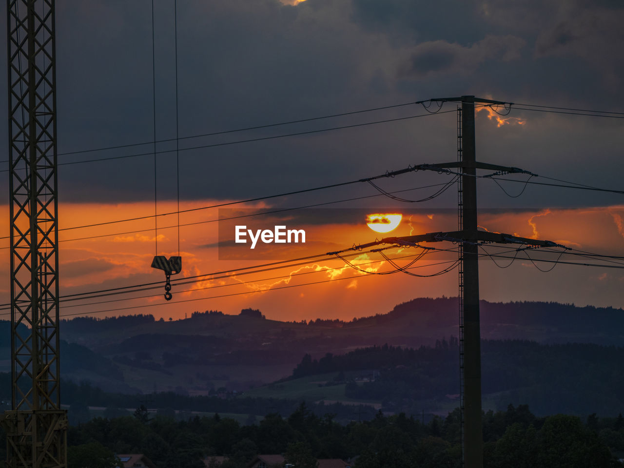 SILHOUETTE ELECTRICITY PYLONS AGAINST ORANGE SKY