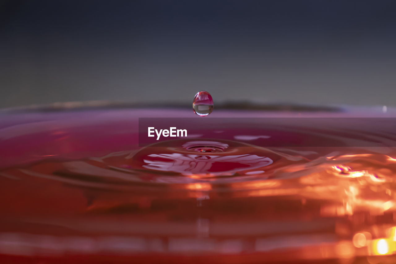 CLOSE-UP OF DROP FALLING ON WATER IN CONTAINER