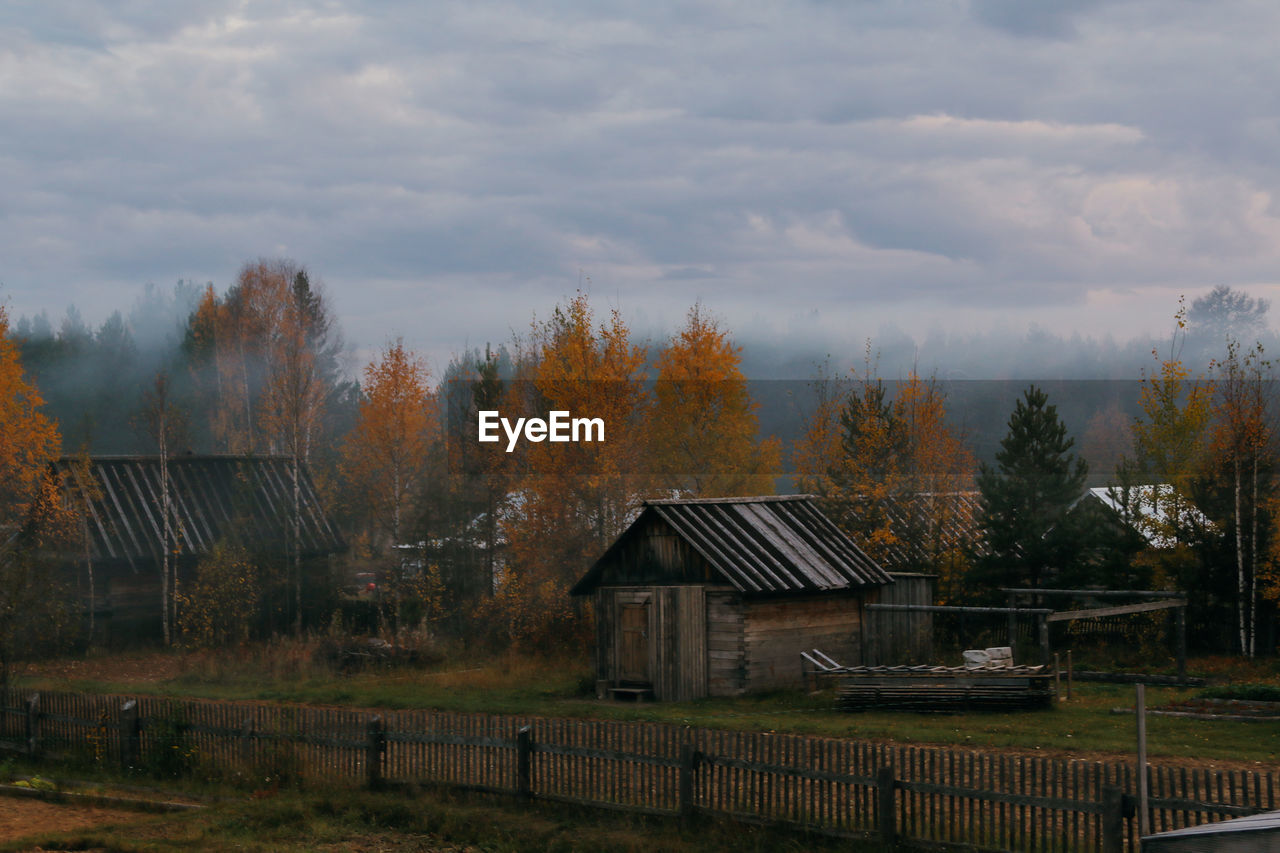 Houses and trees on field against sky