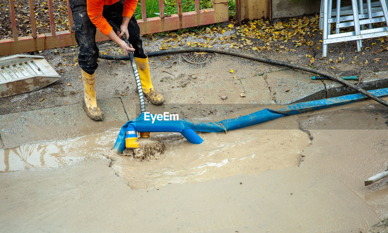 one person, working, men, day, low section, occupation, nature, asphalt, cleaning, high angle view, manual worker, floor, outdoors, construction industry, construction site, human leg, architecture, lifestyles, water, wet