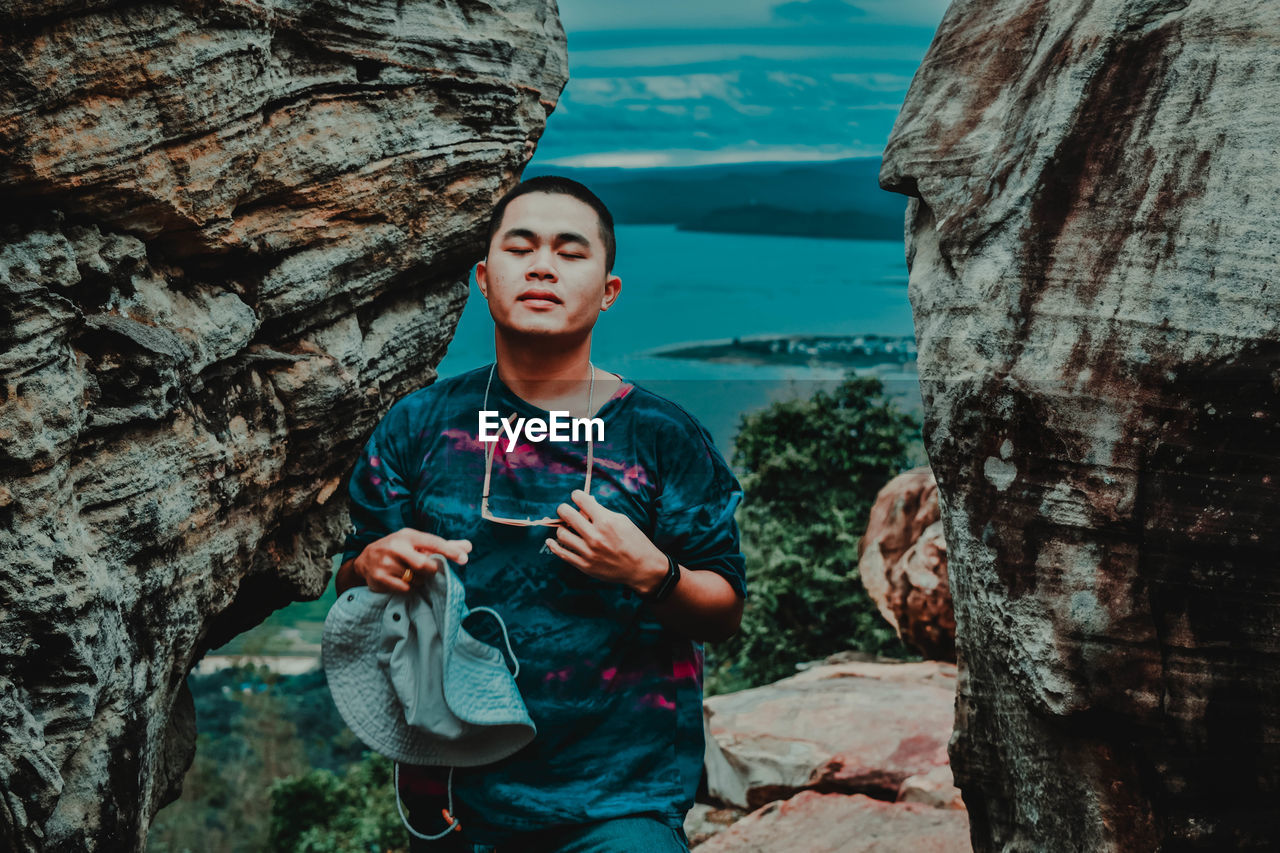 Young man standing on rock against sea