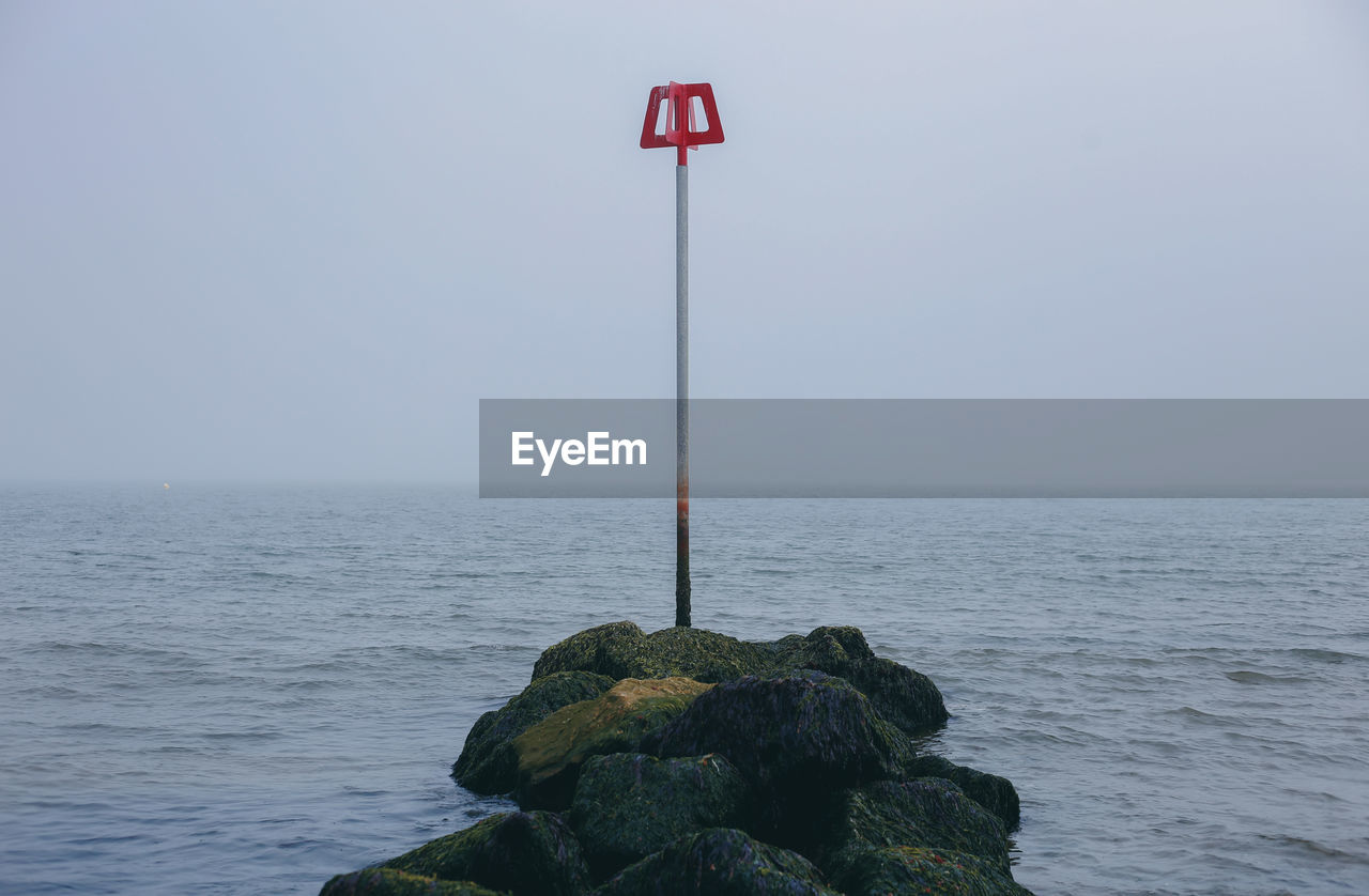 A safety pole on rocks by the sea