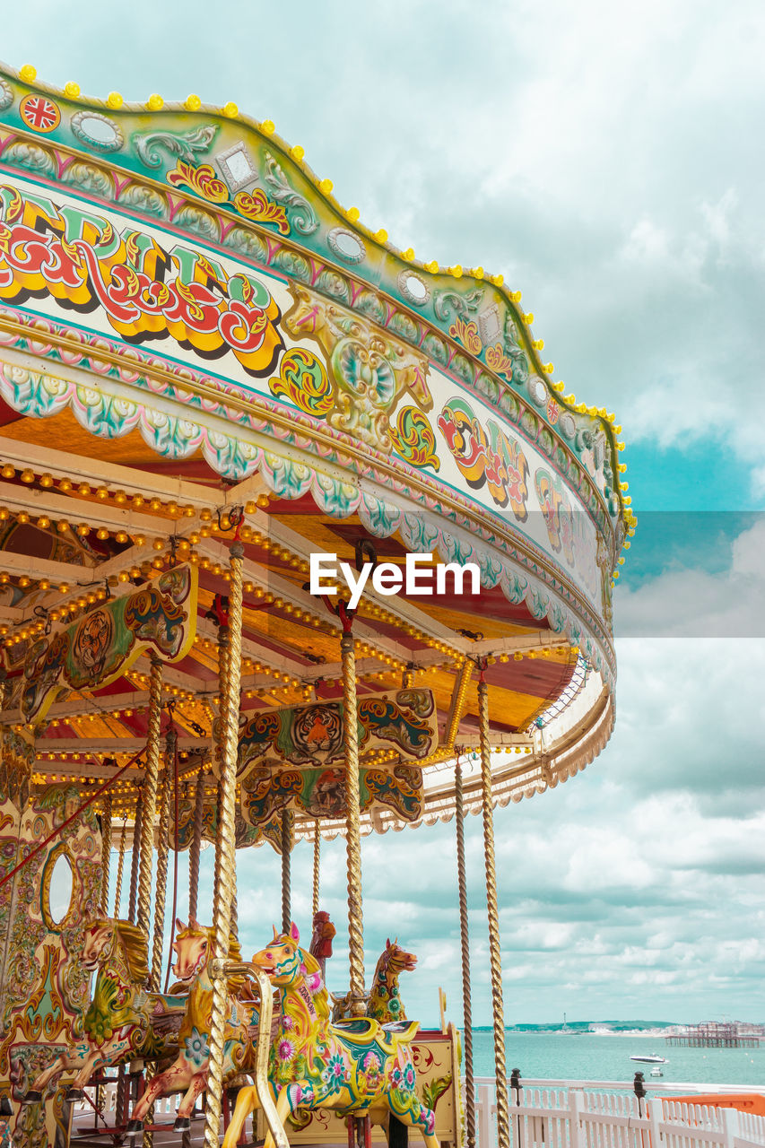 Low angle view of carousel against cloudy sky