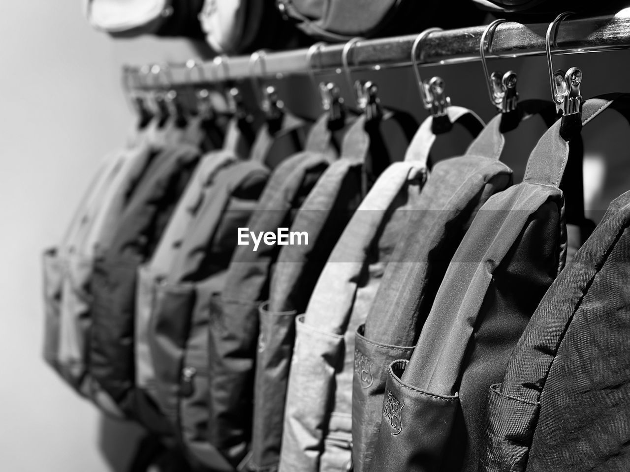 hanging, black, clothing, coathanger, retail, in a row, rack, white, variation, store, large group of objects, no people, shopping, clothes rack, business, fashion, black and white, monochrome, order, indoors