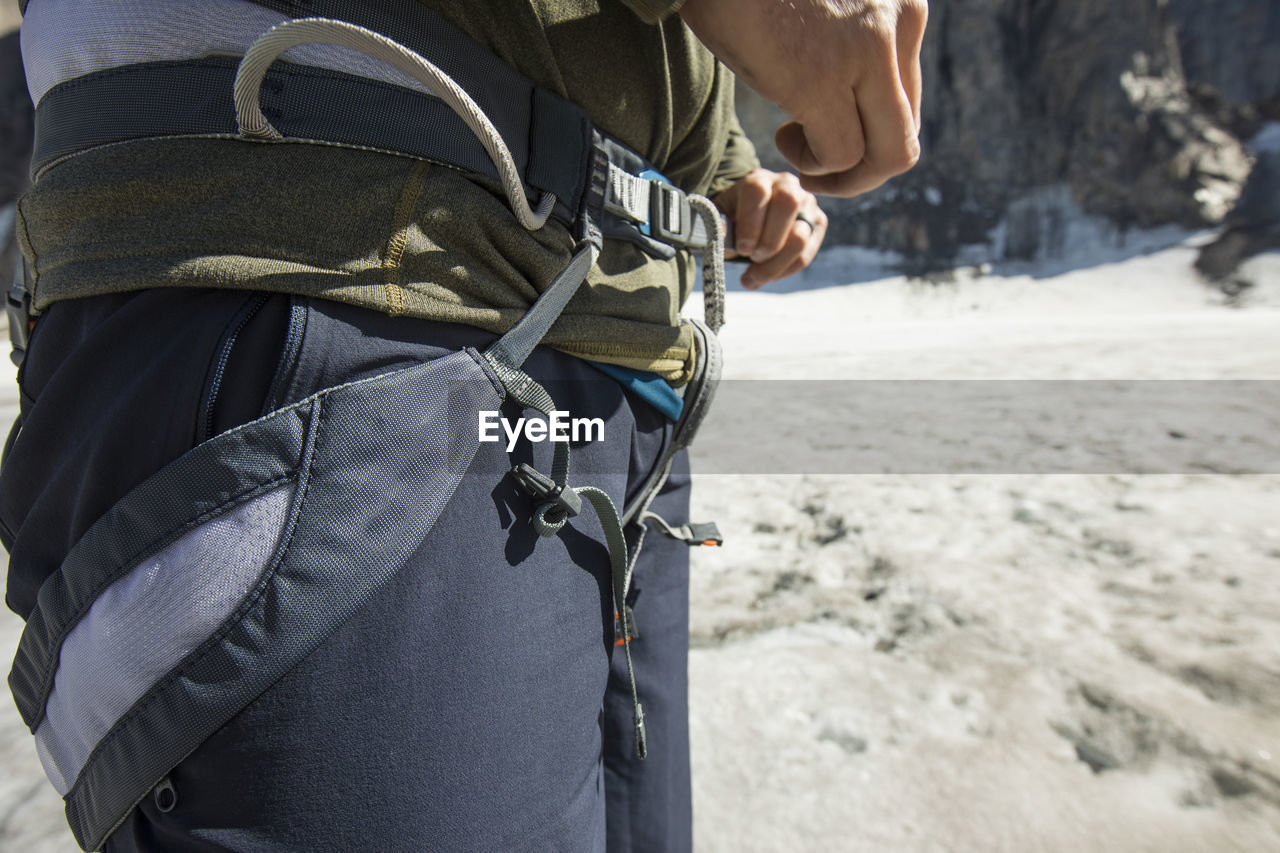 Mountain climber tightens his climbing harness prior to climbing.