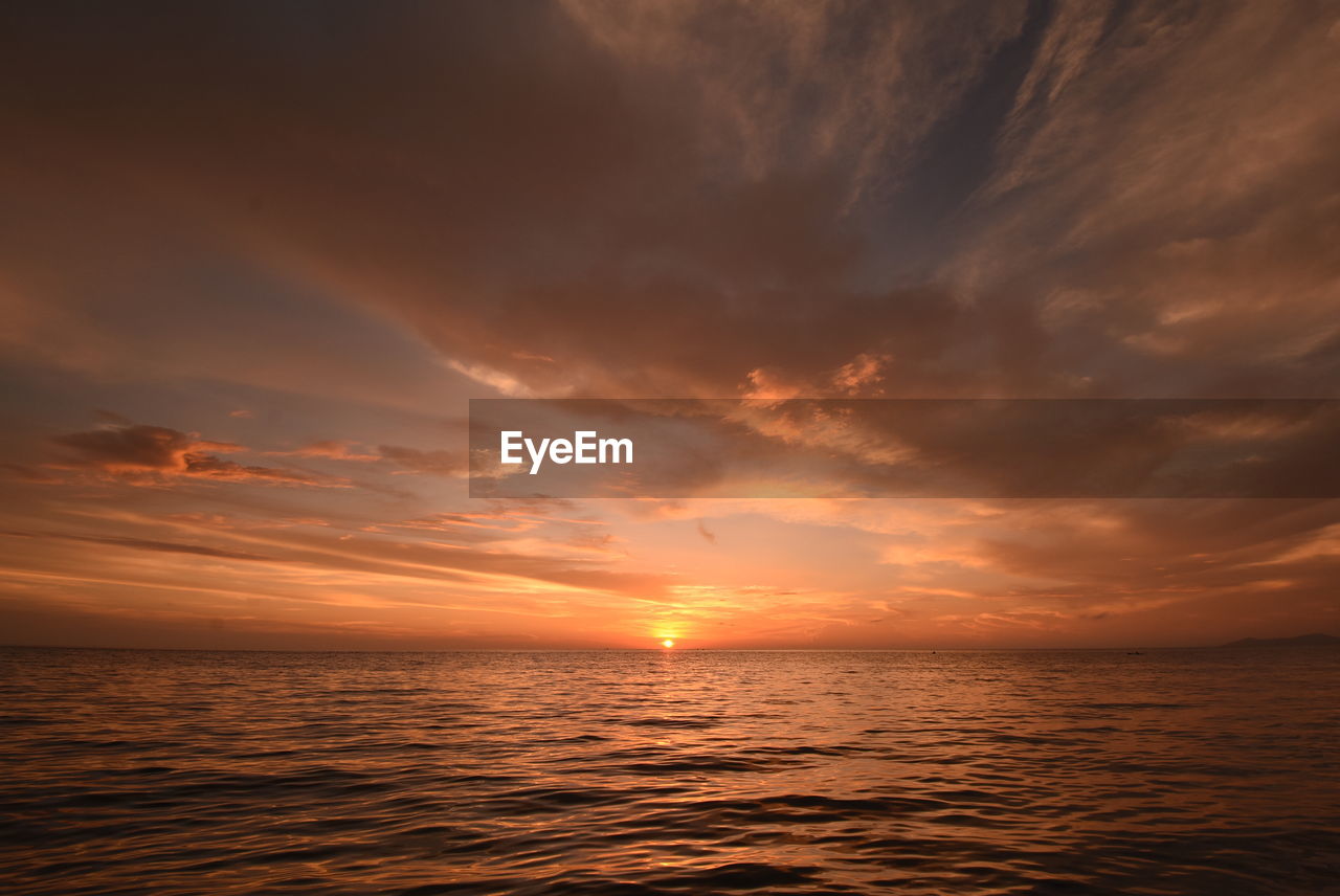 Scenic view of sea against dramatic sky during sunset