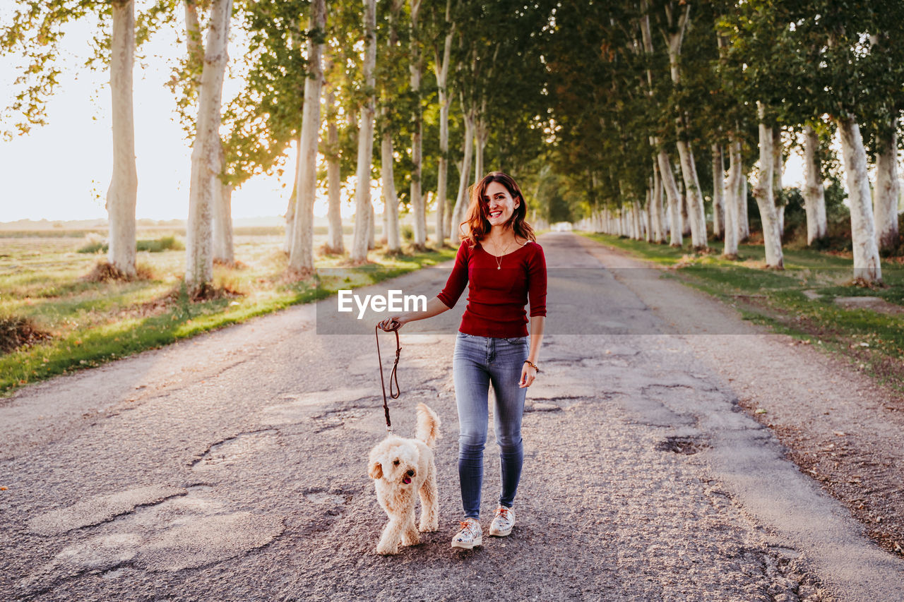 Portrait of woman walking with dog on footpath