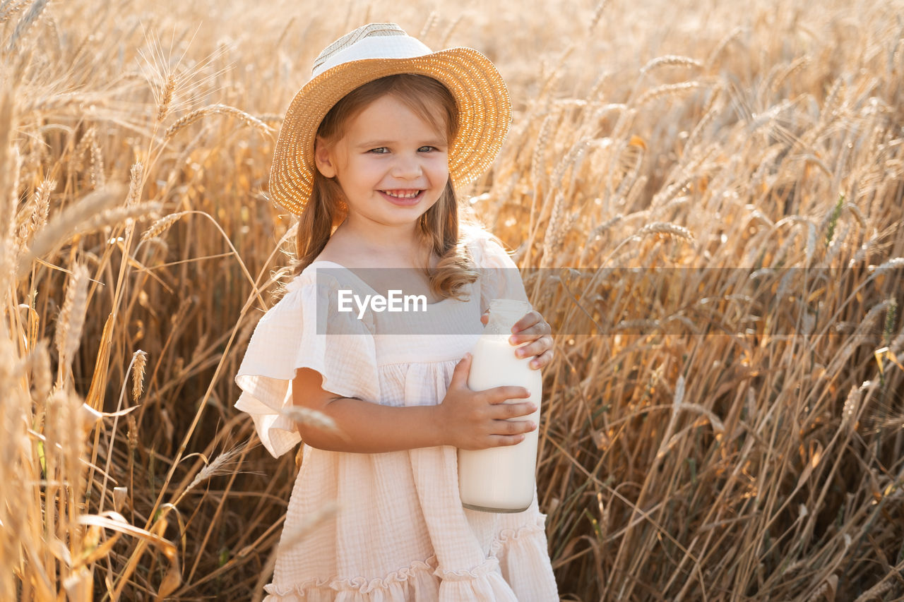 smiling, child, plant, cereal plant, field, childhood, agriculture, happiness, one person, crop, women, rural scene, landscape, emotion, nature, portrait, land, wheat, farm, hat, female, summer, clothing, standing, sun hat, looking at camera, adult, cheerful, growth, food, grass, positive emotion, food grain, long hair, cute, environment, enjoyment, cereal, harvesting, corn, casual clothing, sunlight, waist up, day, outdoors, hairstyle, lifestyles, front view, sky, beauty in nature, three quarter length, meadow, carefree, teeth, innocence, smile, blond hair, barley, person, plain, food and drink, dress, fashion, leisure activity, toddler, copy space