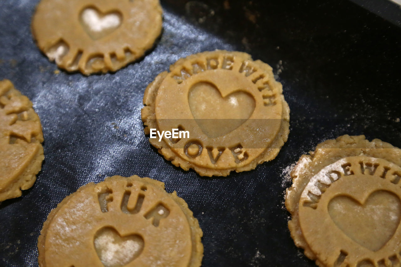 Close-up of raw cookies with text on baking sheet