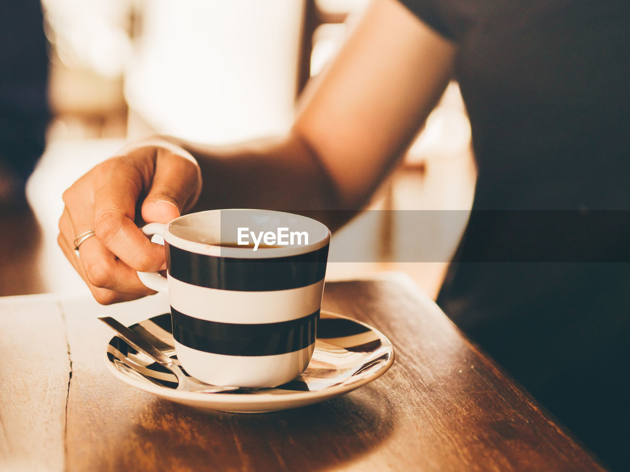 Midsection of woman holding coffee cup on table