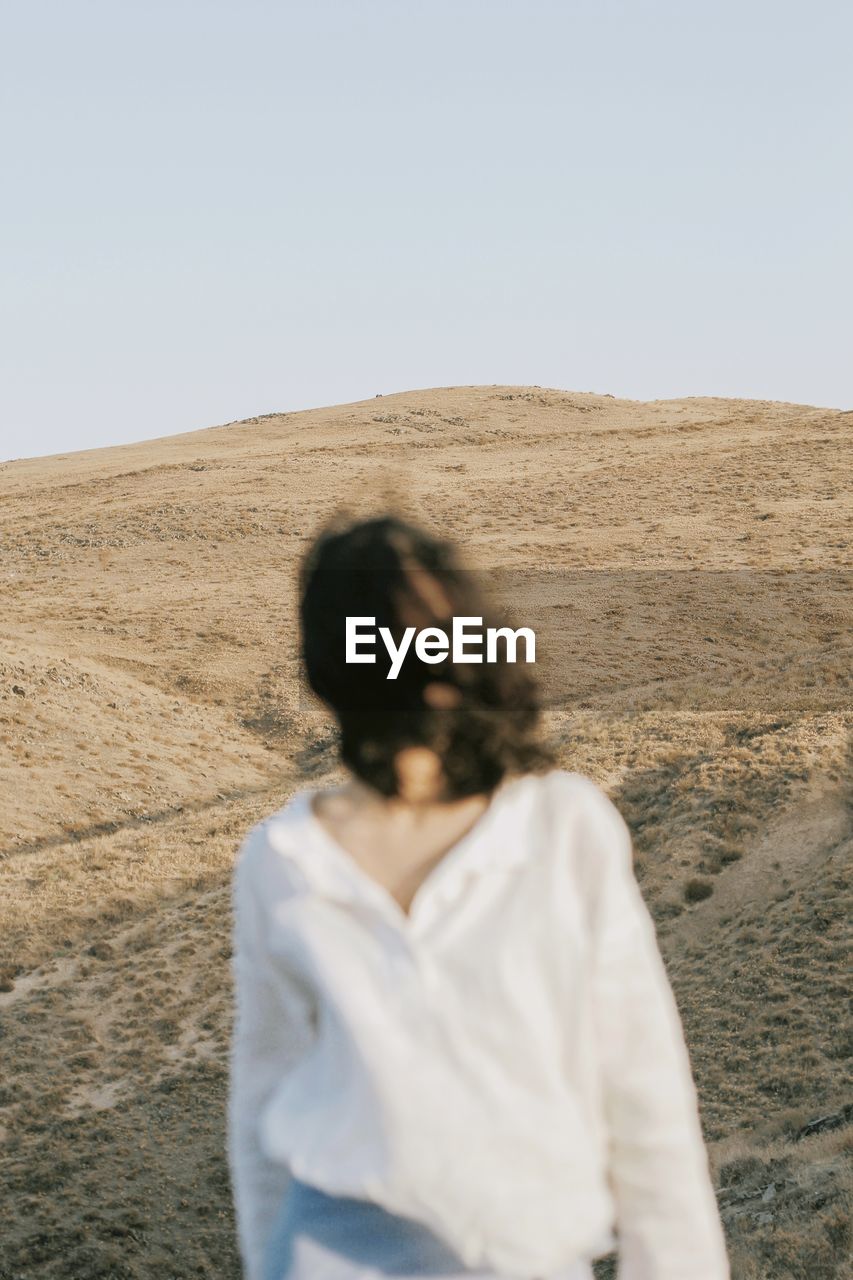 Woman standing on desert against clear sky