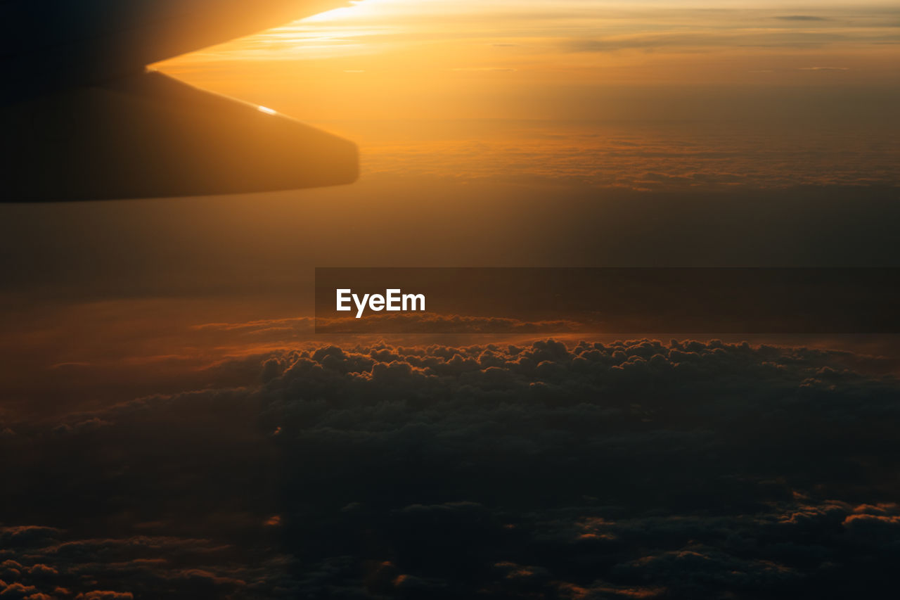 A sunset view on a plane heading to southern europe late in the evening above the clouds