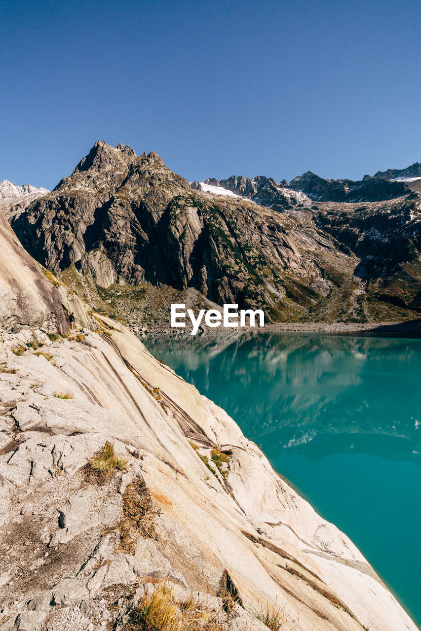 Scenic view of lake and mountains against clear blue sky