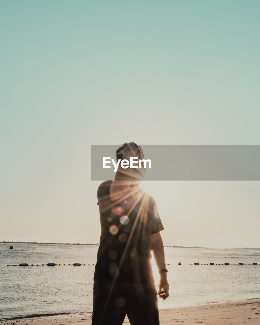 Man standing on beach against clear sky