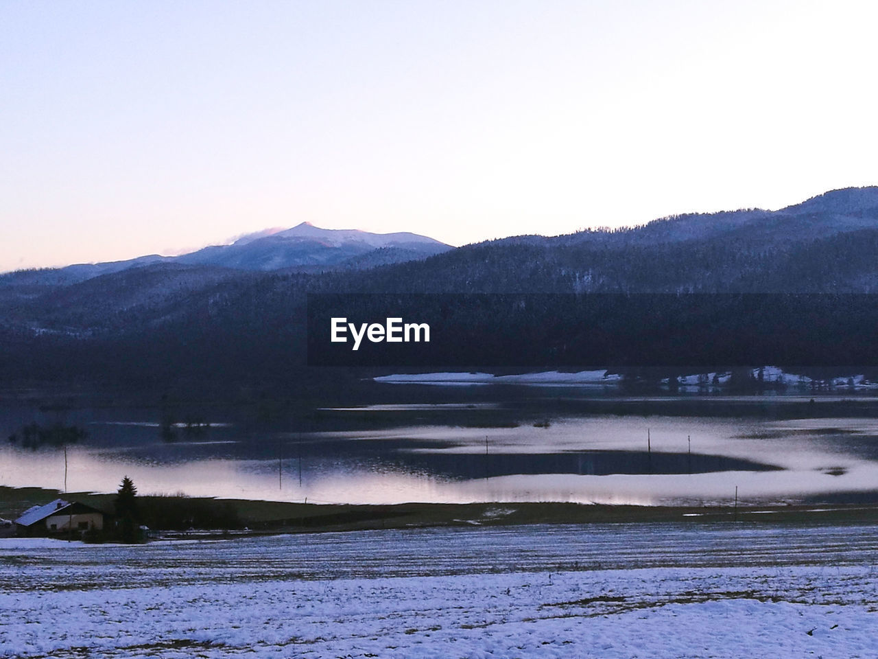 SCENIC VIEW OF FROZEN LAKE AGAINST MOUNTAINS