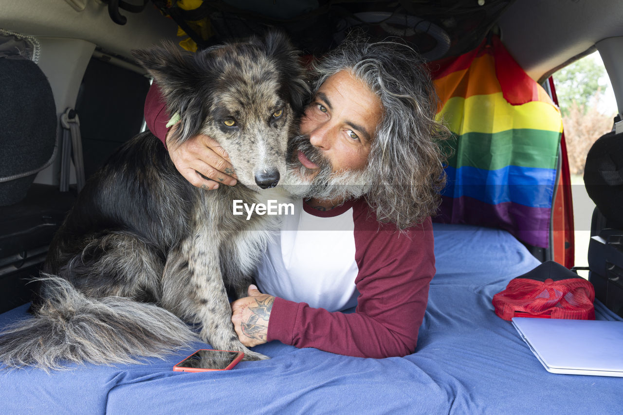 Man hugging his pet inside a mini van digital nomad lifestyle