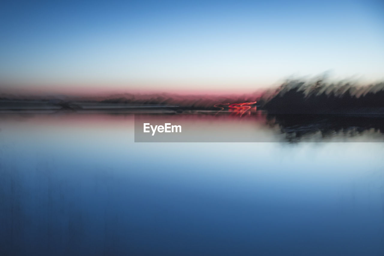 Scenic view of lake against clear sky at sunset