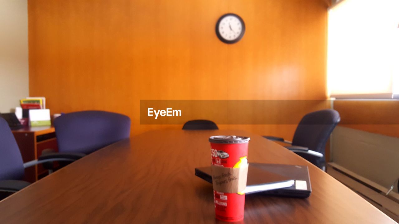 EMPTY CHAIRS AND TABLE AGAINST ORANGE WALL