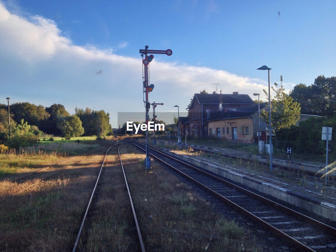 Railroad tracks by house against sky