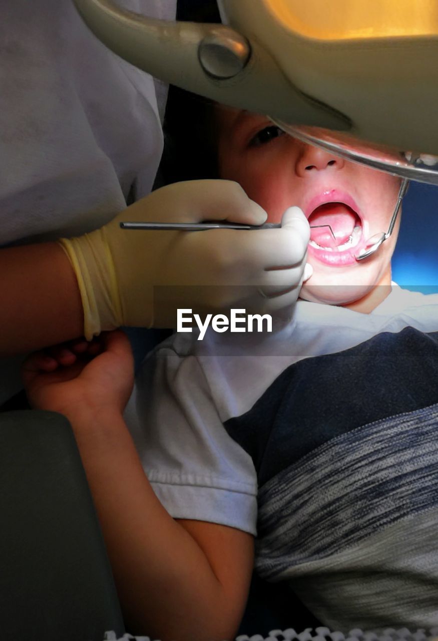 Midsection of dentist examining boy