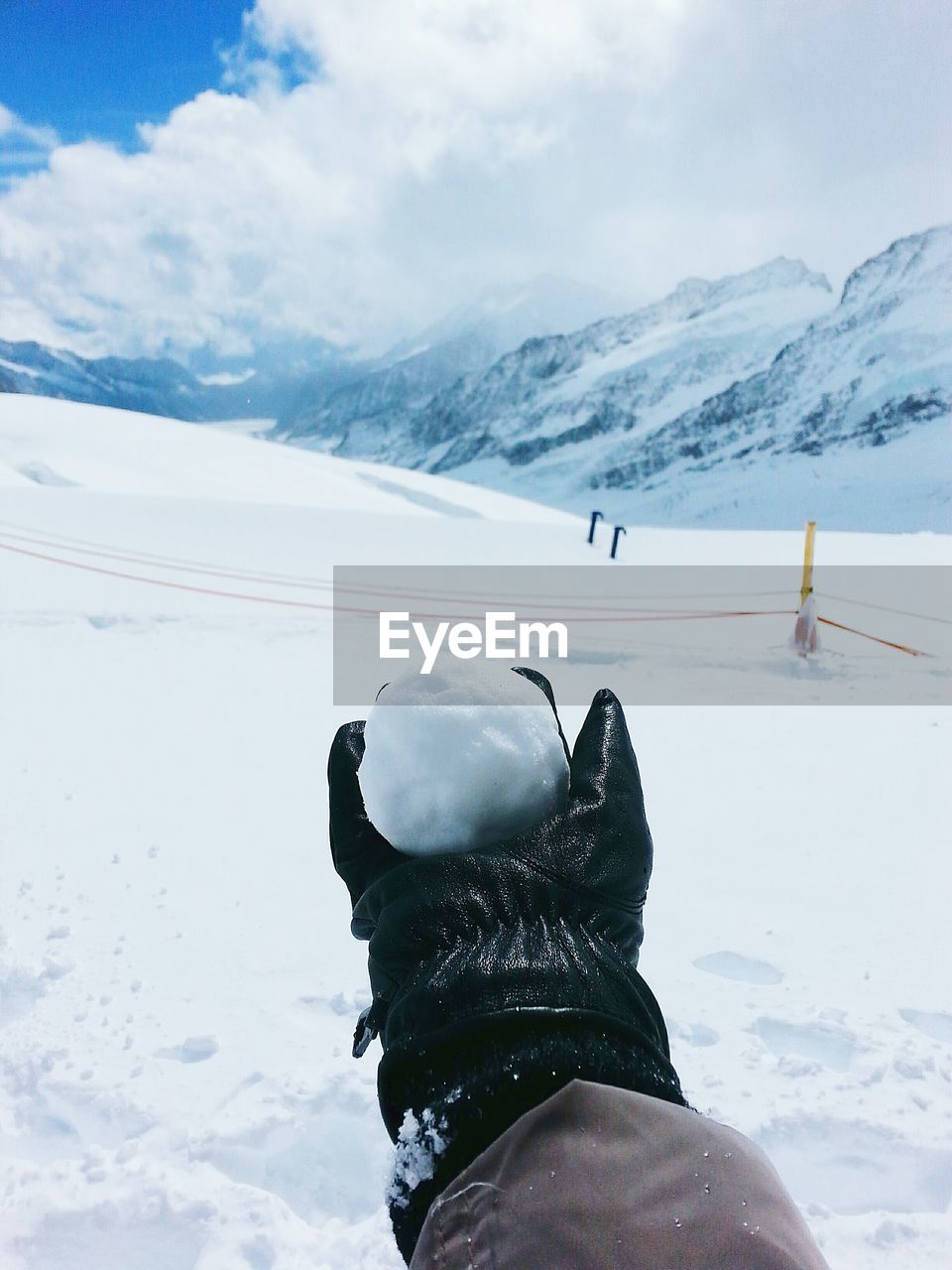 Cropped image of hand holding snowball on snow covered field