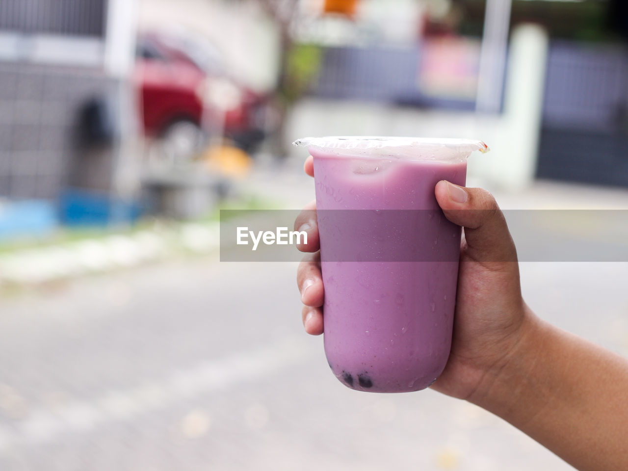 Close up hand holding ice milk taro flavour with bobba inside