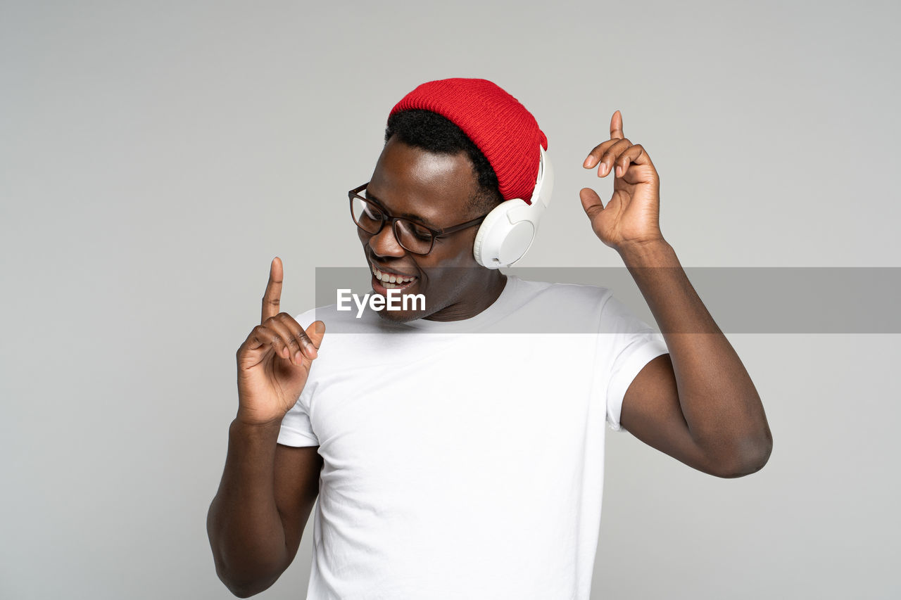 Young man dancing while listening music against white background