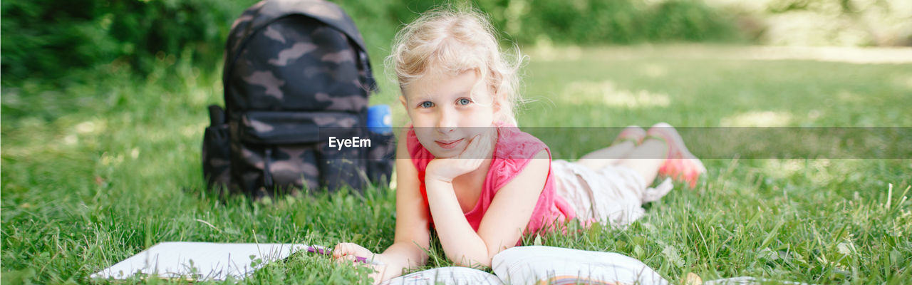 Portrait of cute girl lying on grass at park