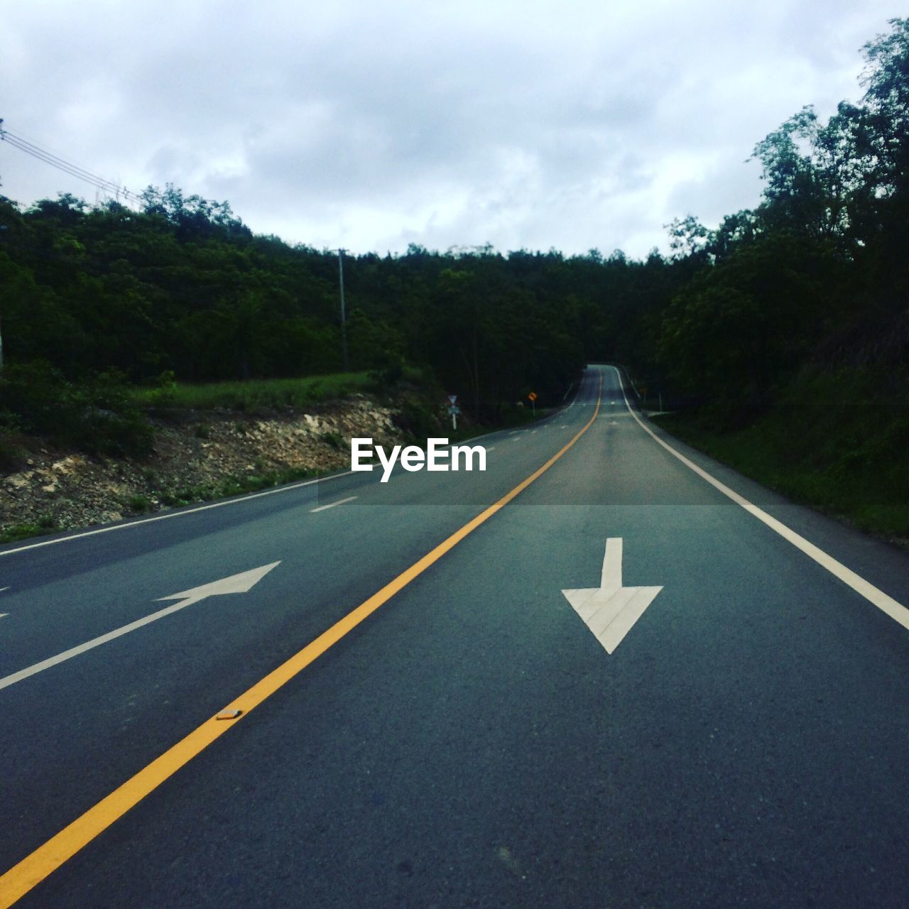 High angle view of arrow sign on empty road at dusk