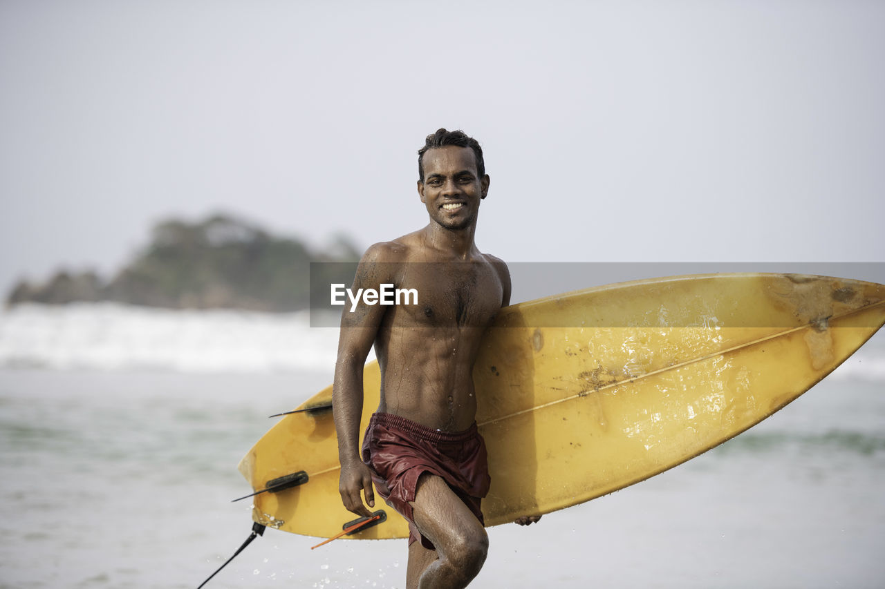 Young man standing by sea against sky