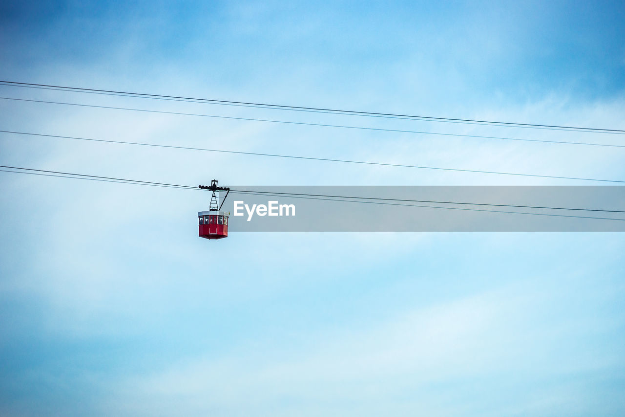Low angle view of overhead cable car against cloudy sky
