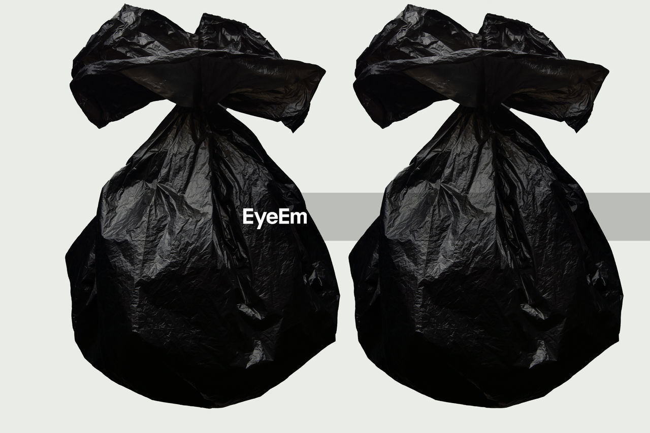 Two garbage bag sorting household waste with black garbage bags