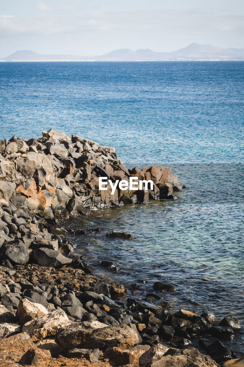 Scenic view of rocks in sea against sky in lanzarote 