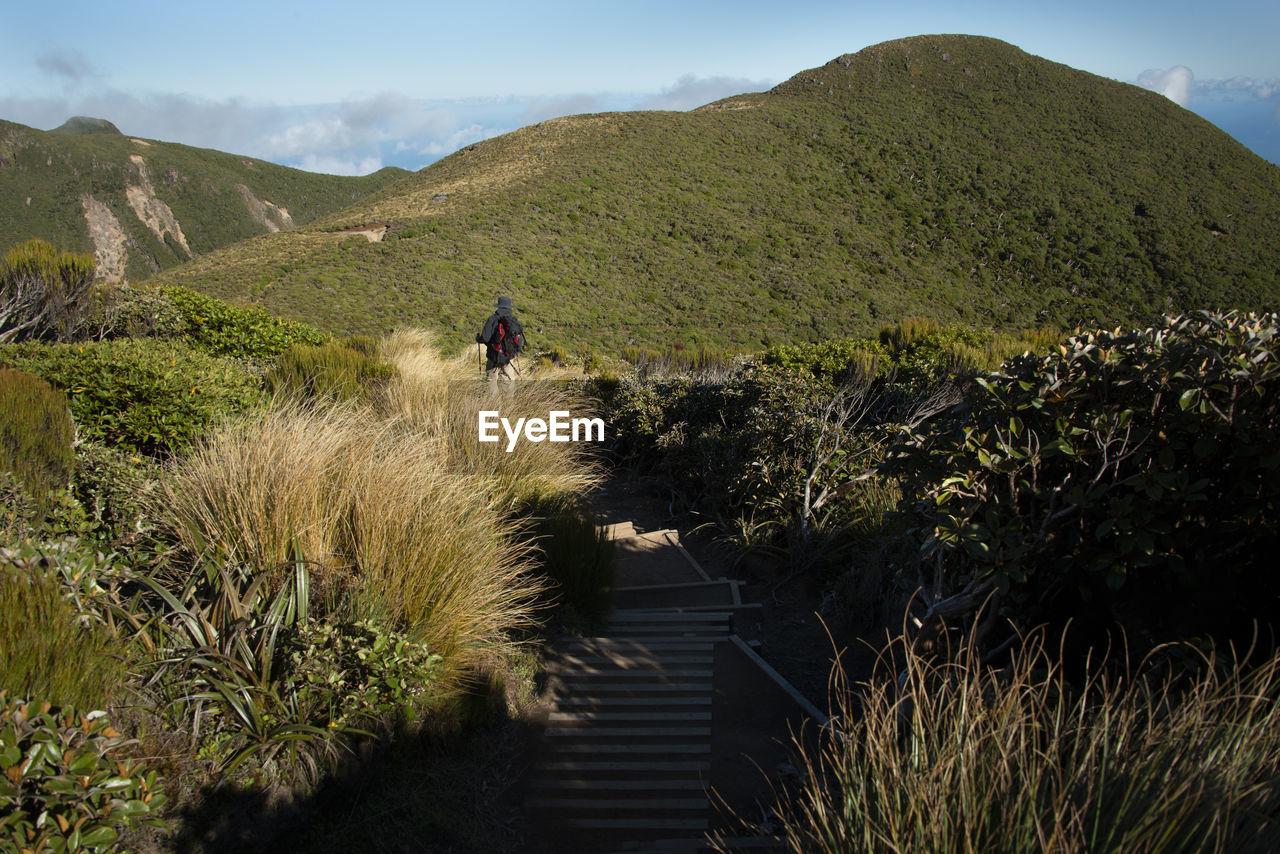 People riding bicycle on footpath by mountains