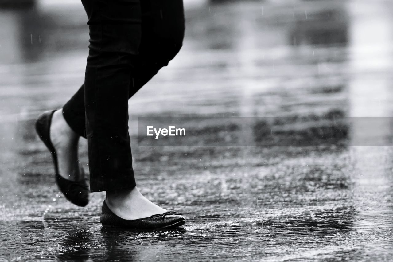 Low section of woman walking on wet footpath