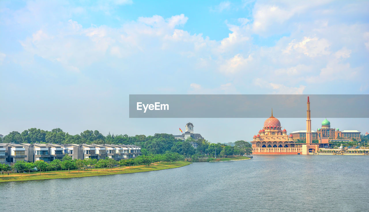 RIVER PASSING THROUGH BUILDING AGAINST CLOUDY SKY