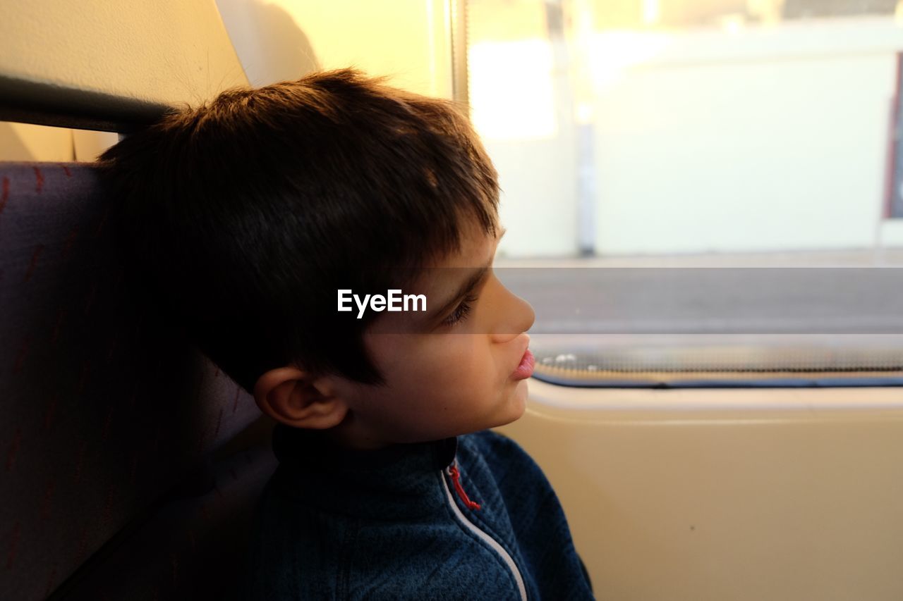 Close-up of boy sitting by window