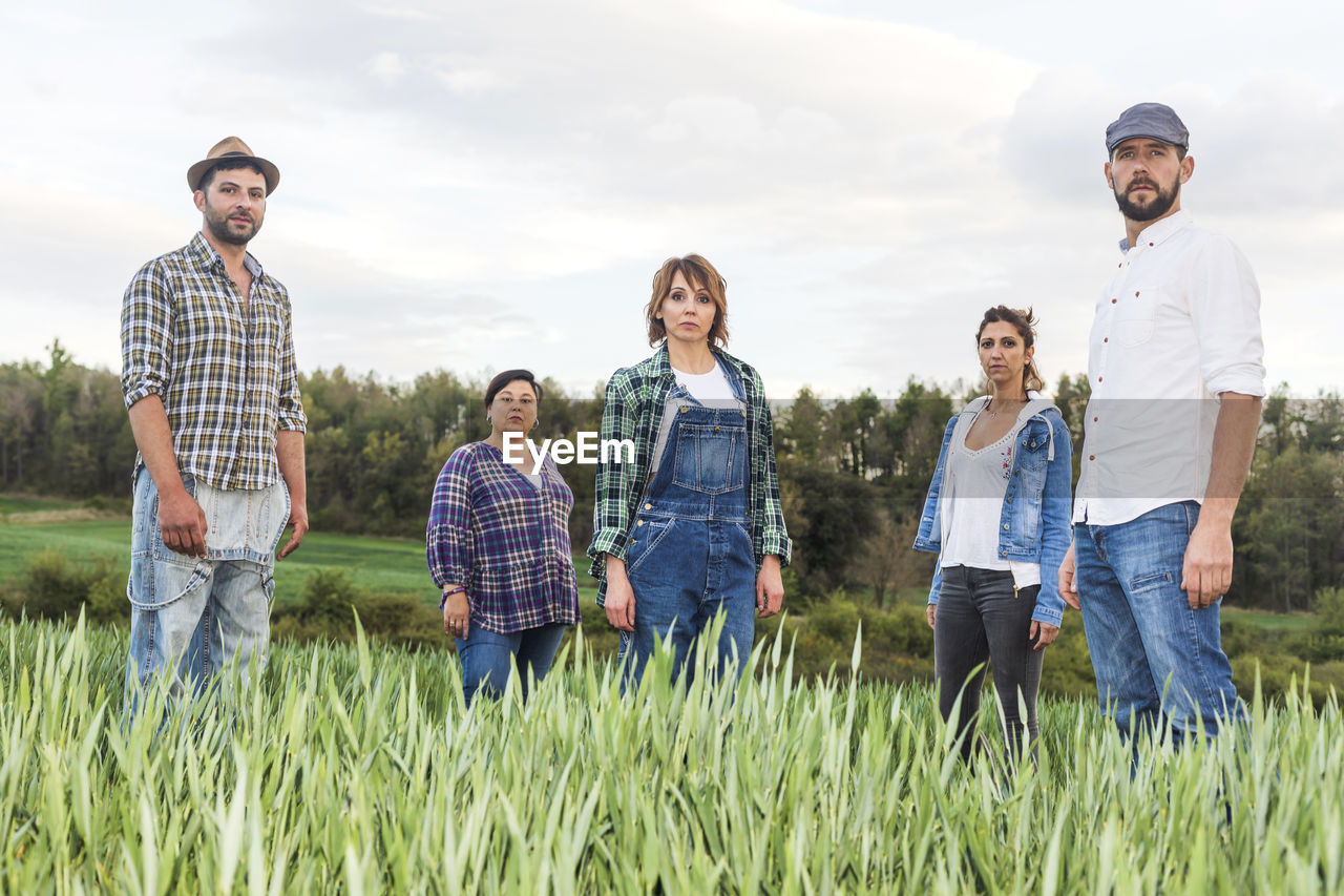 Portrait farmers standing on farm against sky during sunset