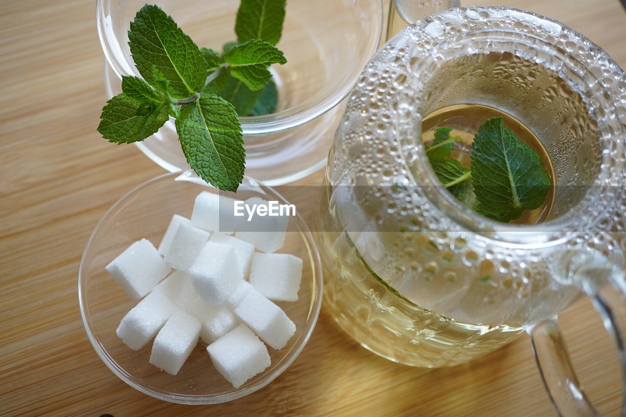 food and drink, leaf, food, herb, mint leaf - culinary, plant part, drink, refreshment, glass, produce, drinking glass, freshness, indoors, household equipment, table, no people, plant, nature, wellbeing, high angle view, healthy eating, spearmint, still life, sugar, fruit, alcohol, wood, tea, crockery