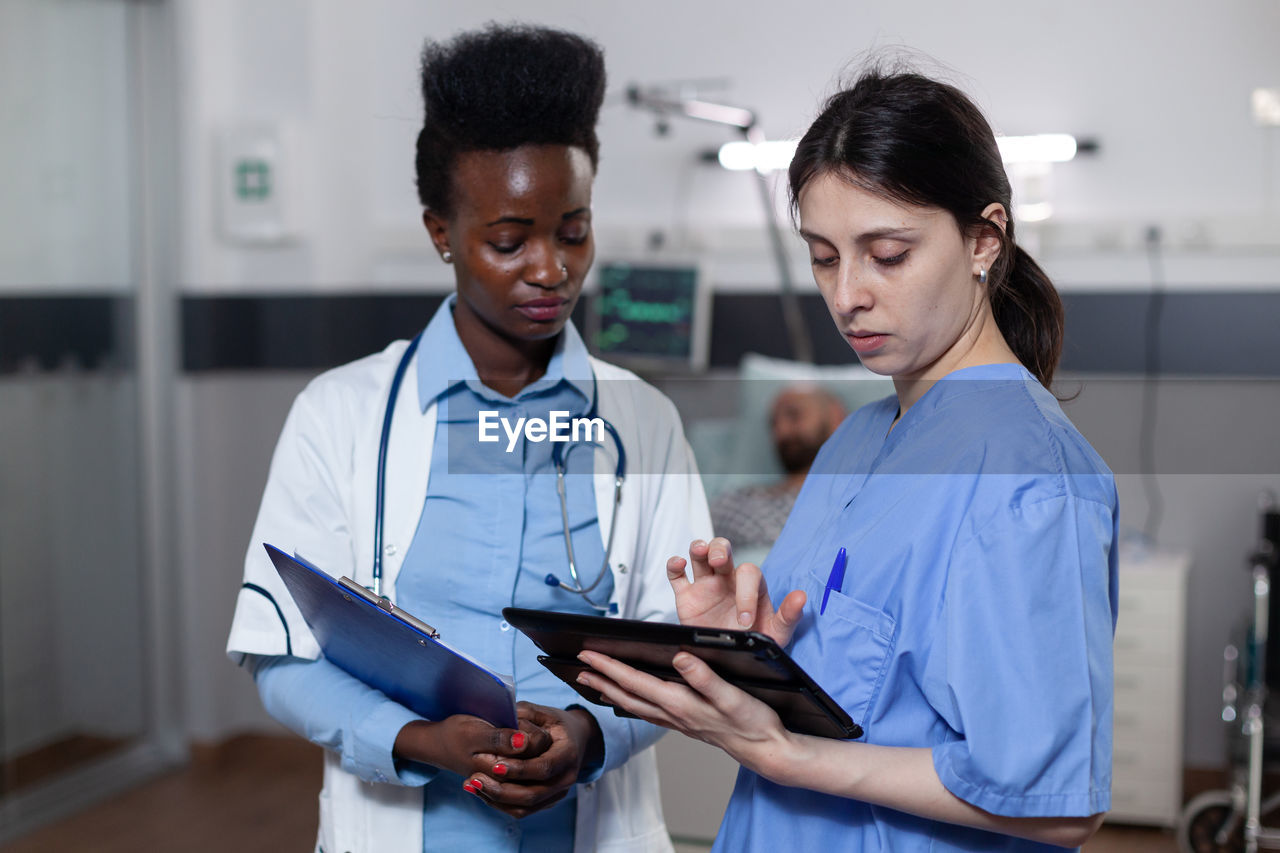 portrait of doctor using mobile phone while standing at clinic