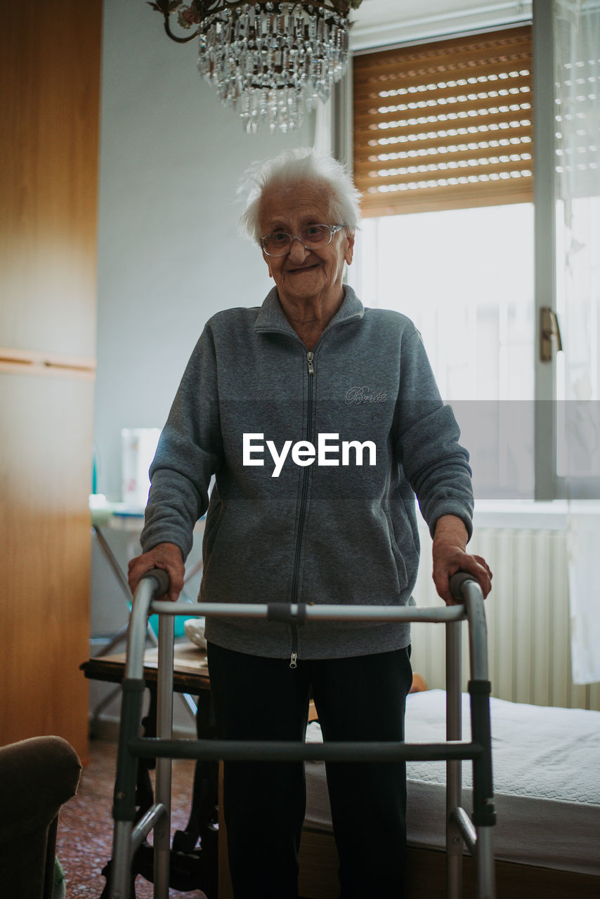 Portrait of senior woman with walker standing at home