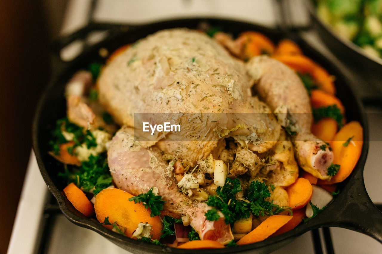 High angle view of chicken with vegetables in frying pan on table