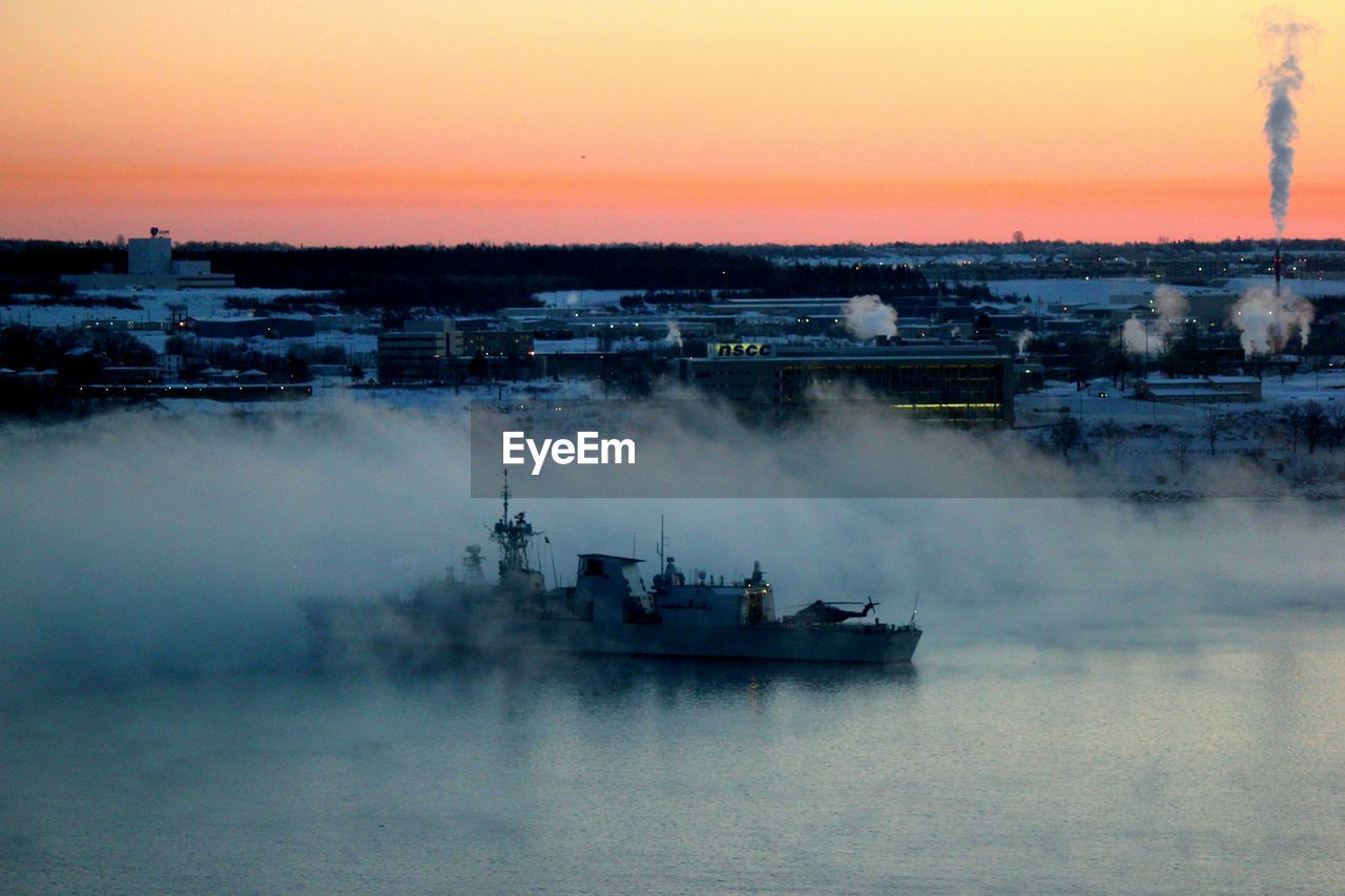 Navy frigate leaving harbor at dawn